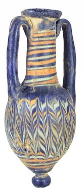 Core-formed dark blue glass Amphoriskos, wound with blue, brown, and light green marbled festoons, the rim and shoulder with two blue glass handles, knobbed foot. The making of core-formed glass vessels was one of the oldest glass making techniques. Some encrustations.